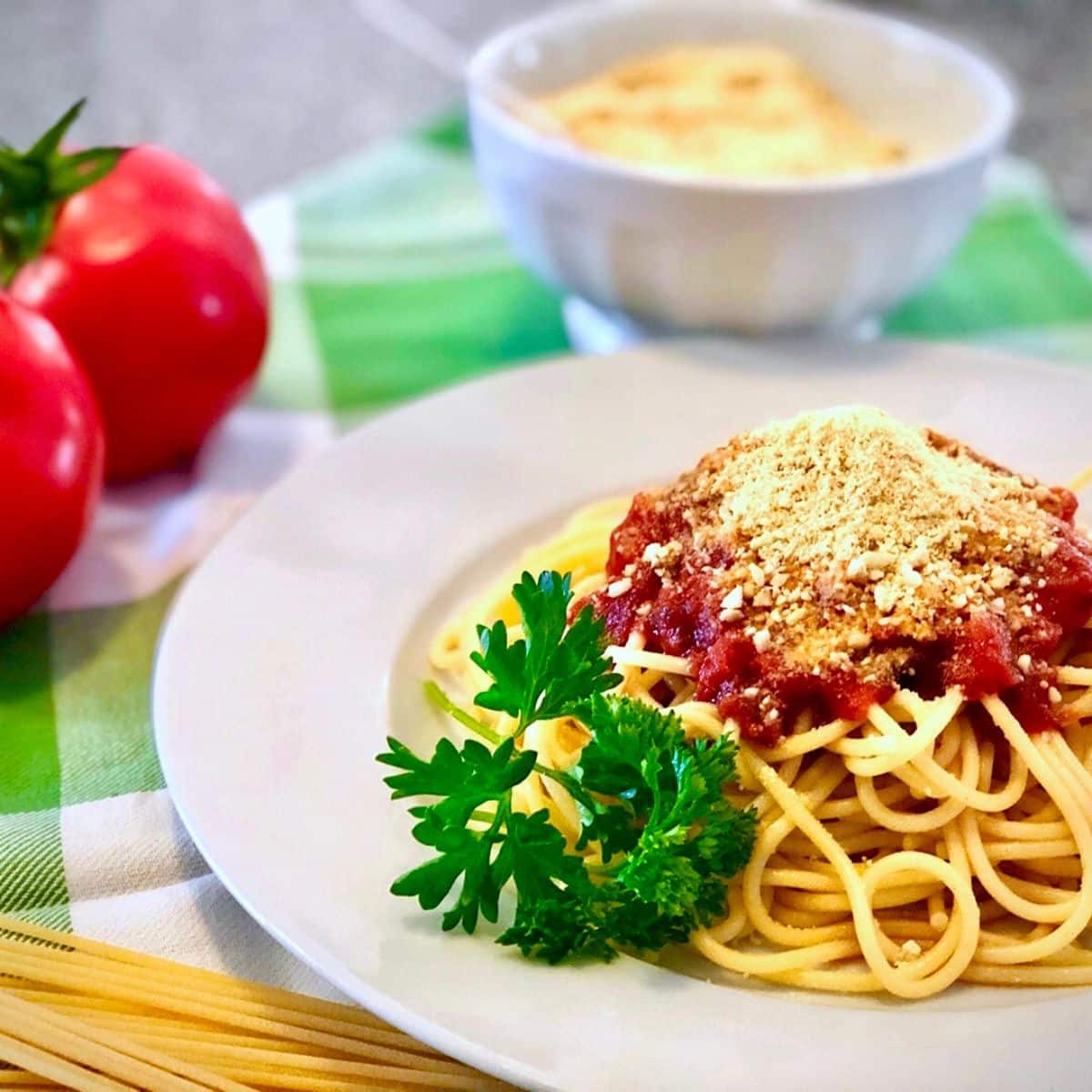 A plate of spaghetti topped with homemade marinara sauce and vegan parmesan cheese.