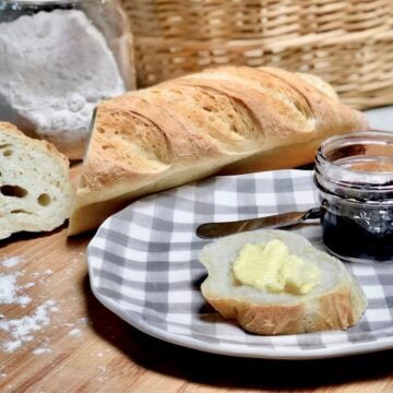 A slice of baguette with a pat of homemade vegan butter spread on top.