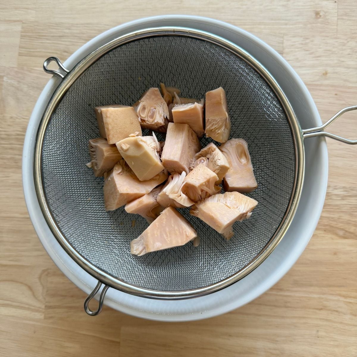 Chunks of canned jackfruit inside a sieve.