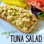 A plate with an open-face vegan tuna salad sandwich and pickle slices.