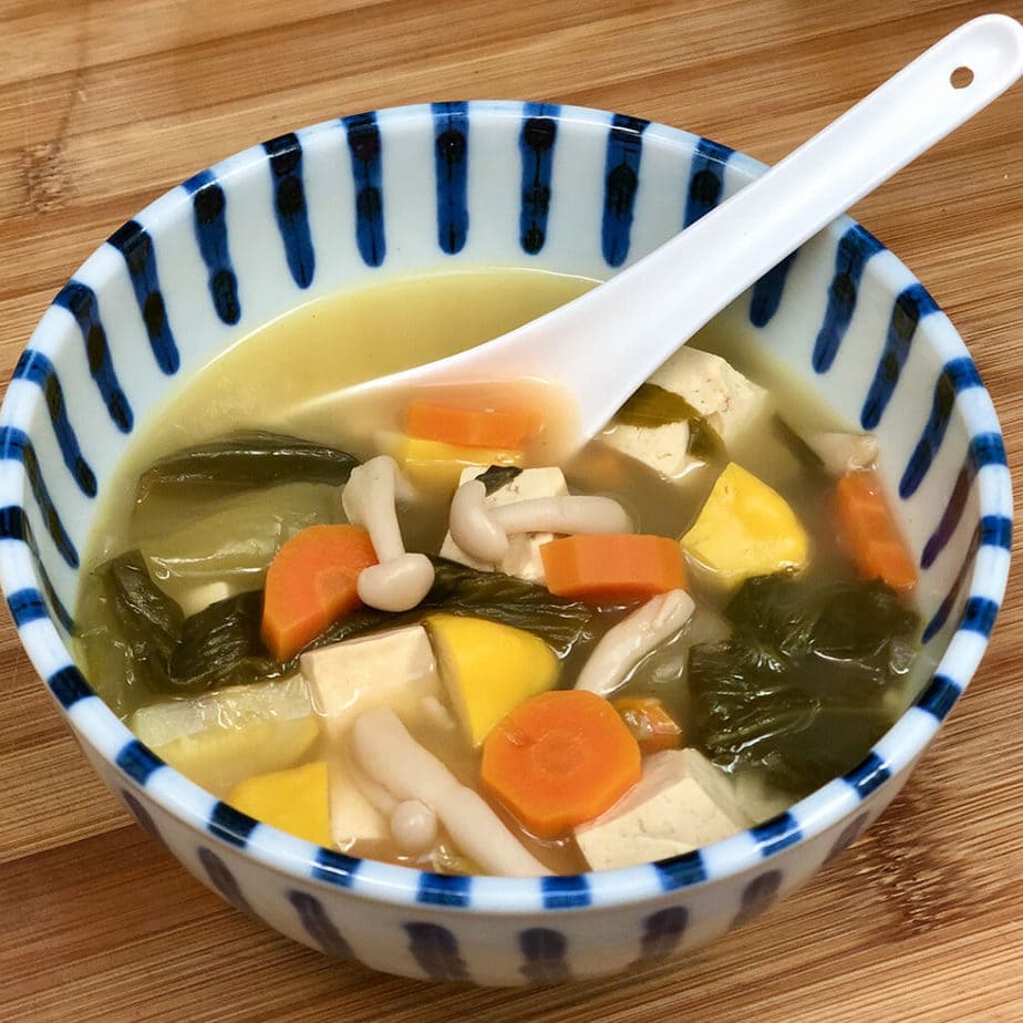 A blue and white striped bowl filled with the best vegan tom yum soup.