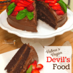 A vegan devils food cake iced in fudge frosting and decorated with fresh strawberries.