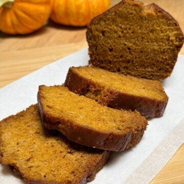 A sliced loaf of vegan pumpkin bread with applesauce.