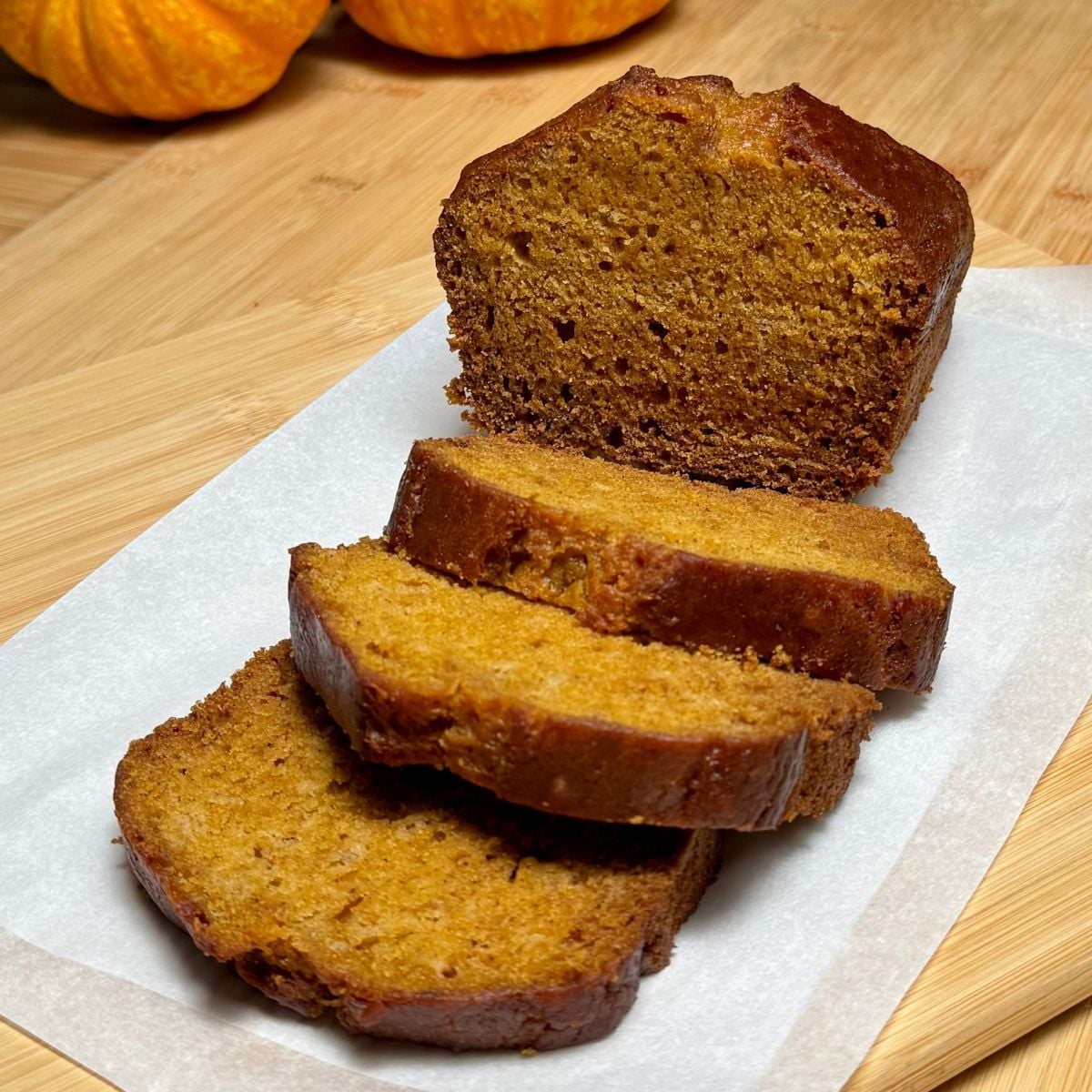 A sliced loaf of vegan pumpkin bread with applesauce.