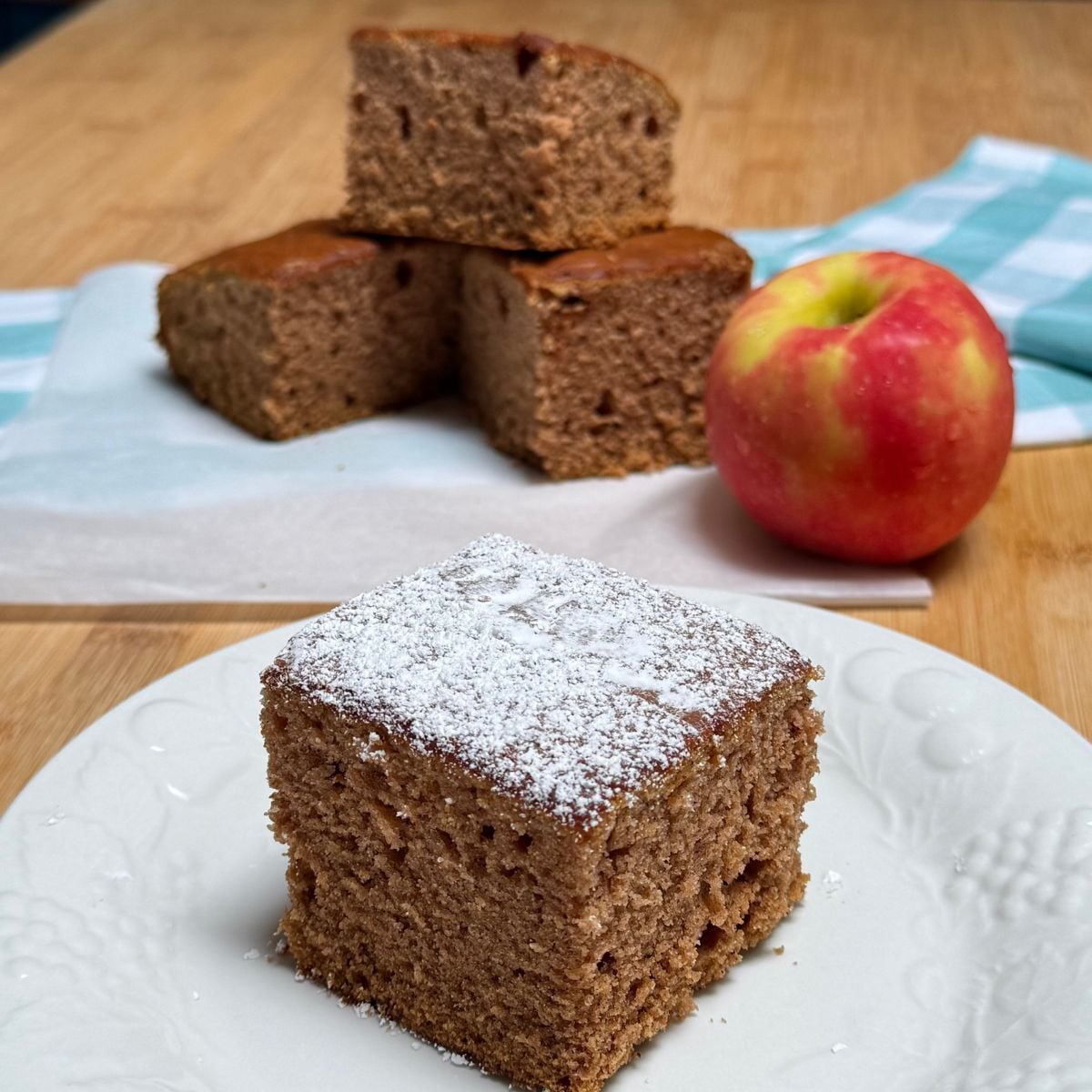 A slice of vegan applesauce cake dusted with powdered sugar.
