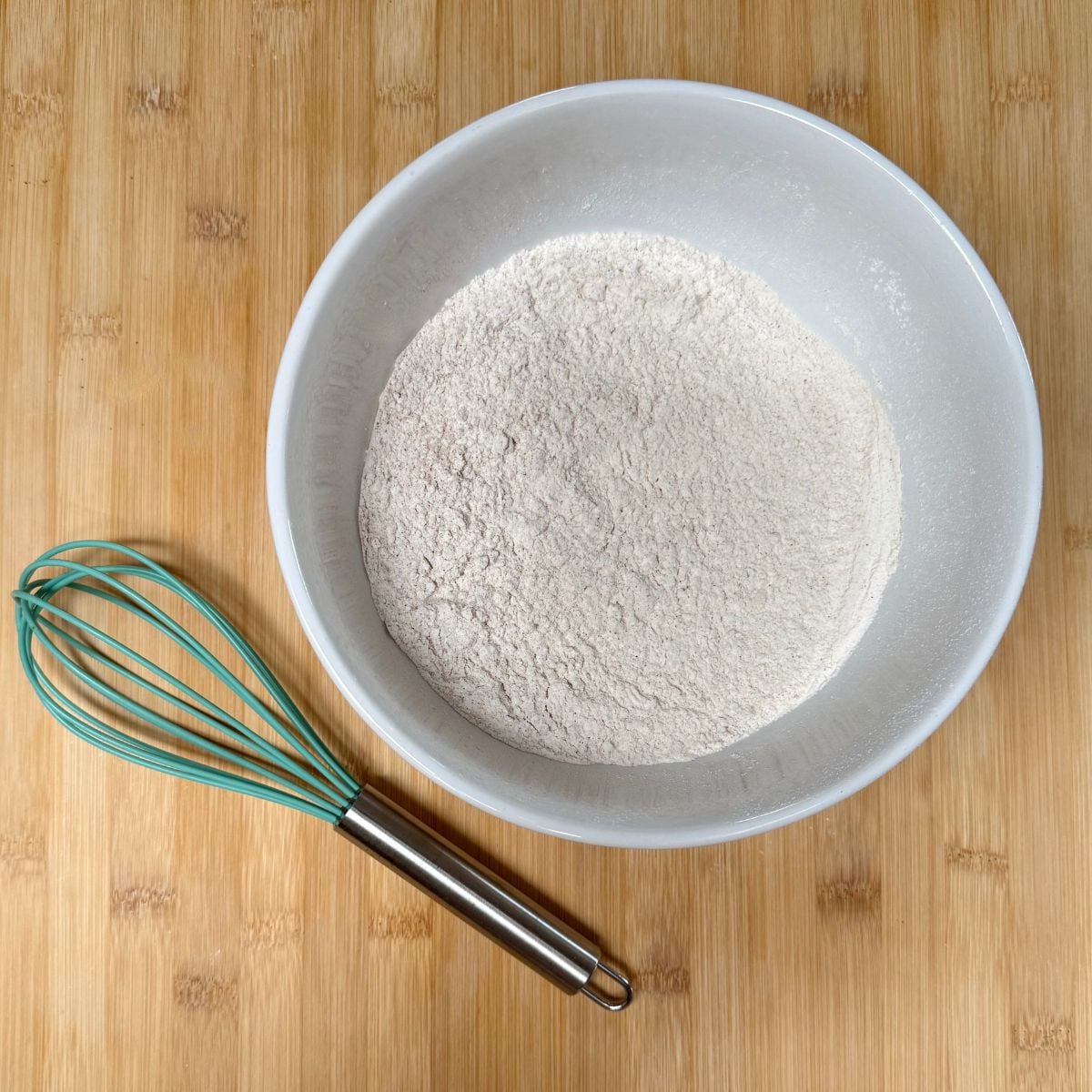 A mixing bowl with flour, salt, baking soda, cinnamon, nutmeg, and cloves.