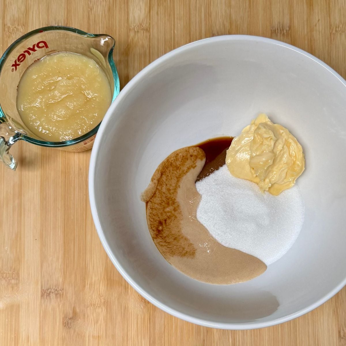 A mixing bowl with ingredients for vegan applesauce cake.