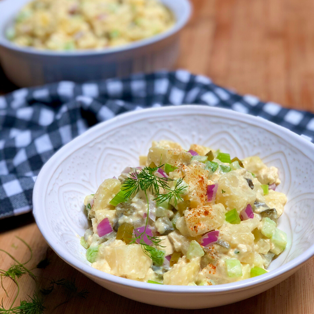 A white bowl filled with vegan old fashioned potato salad.