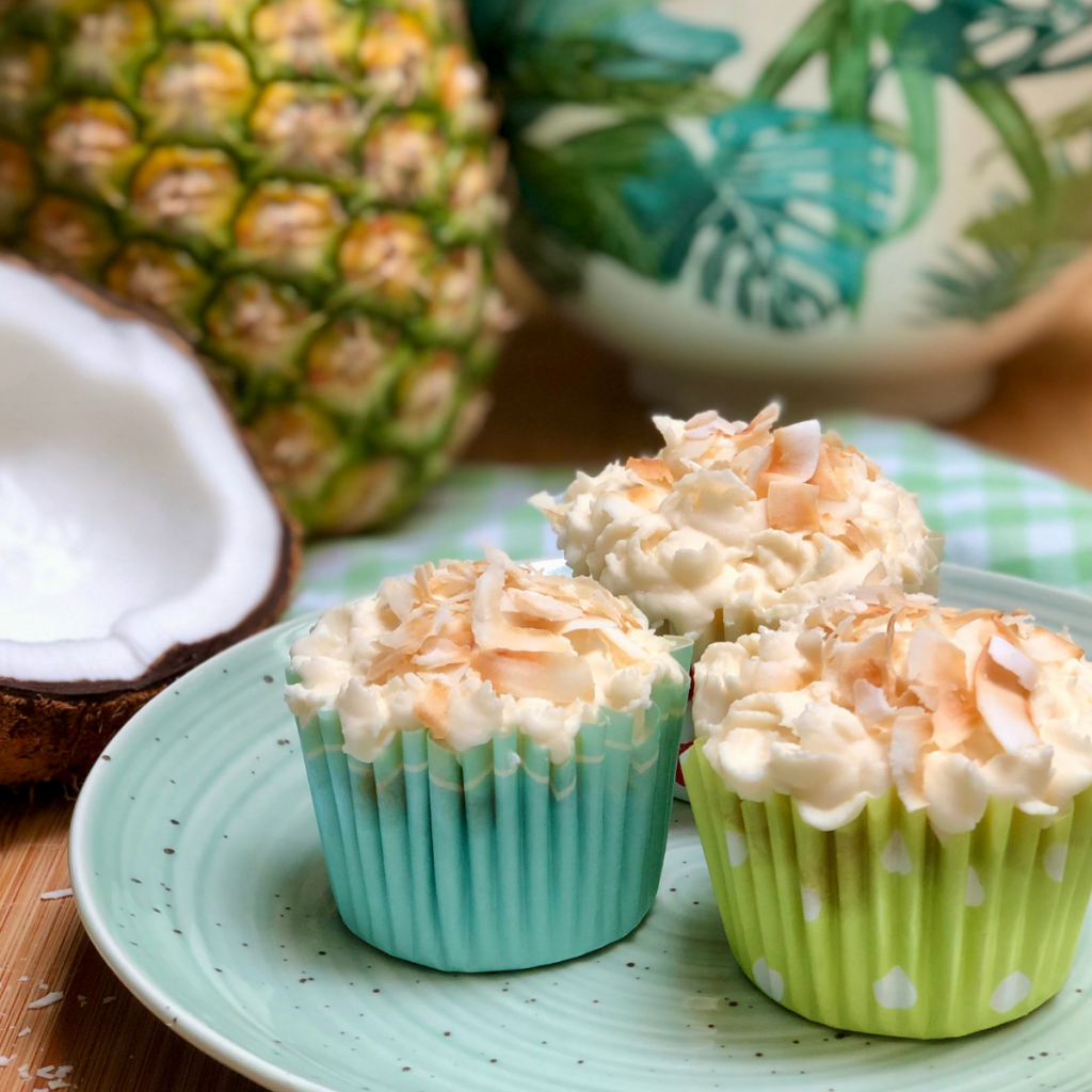Three pineapple coconut cupcakes on a plate.