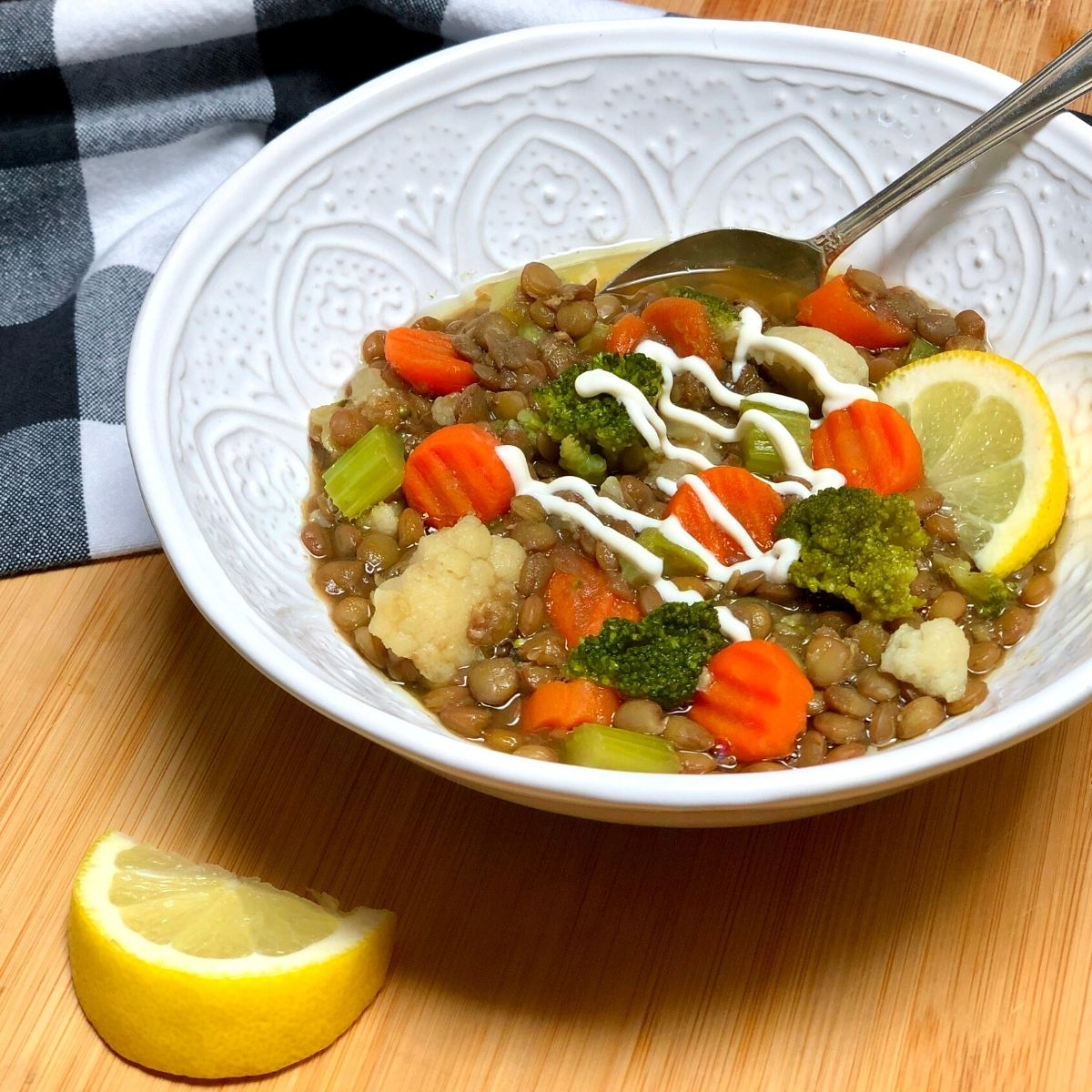 A bowl filled with vegan lentil veggie soup with carrots, broccoli, cauliflower & celery.