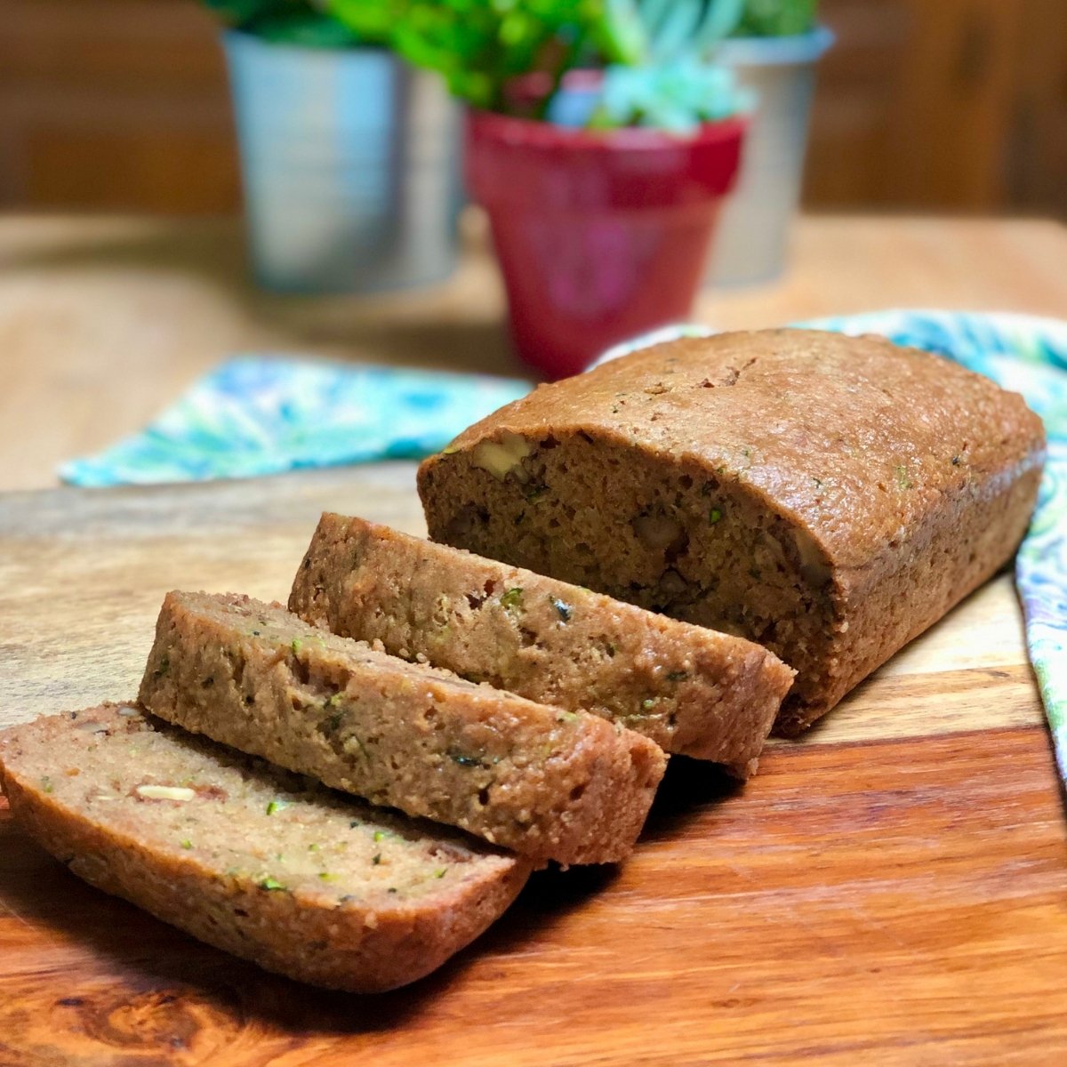 A sliced loaf of vegan zucchini bread on a cutting board.