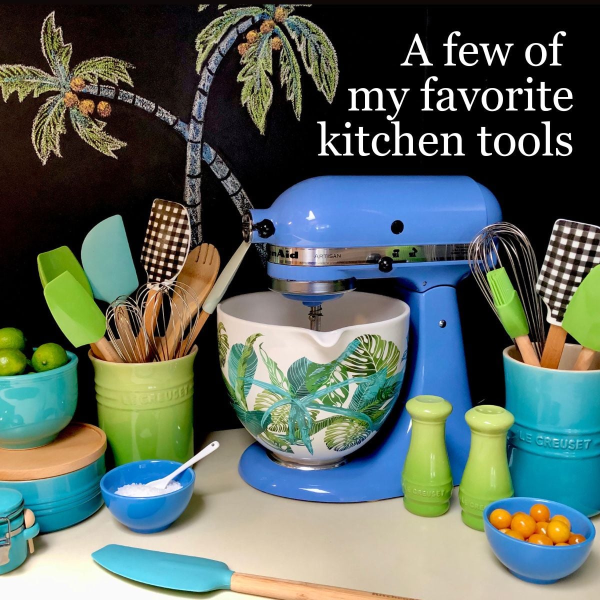 A collection of kitchen tools including a KitchenAid stand up mixer and bow, crocks of spatulas, whisks, and wooden spoons.