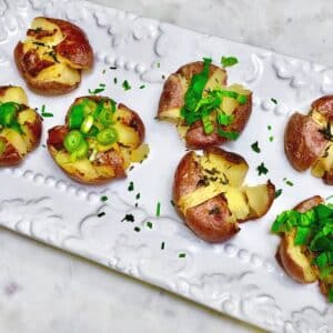 A plate with vegan cuban crushed potatoes topped with sliced chives and green onions.