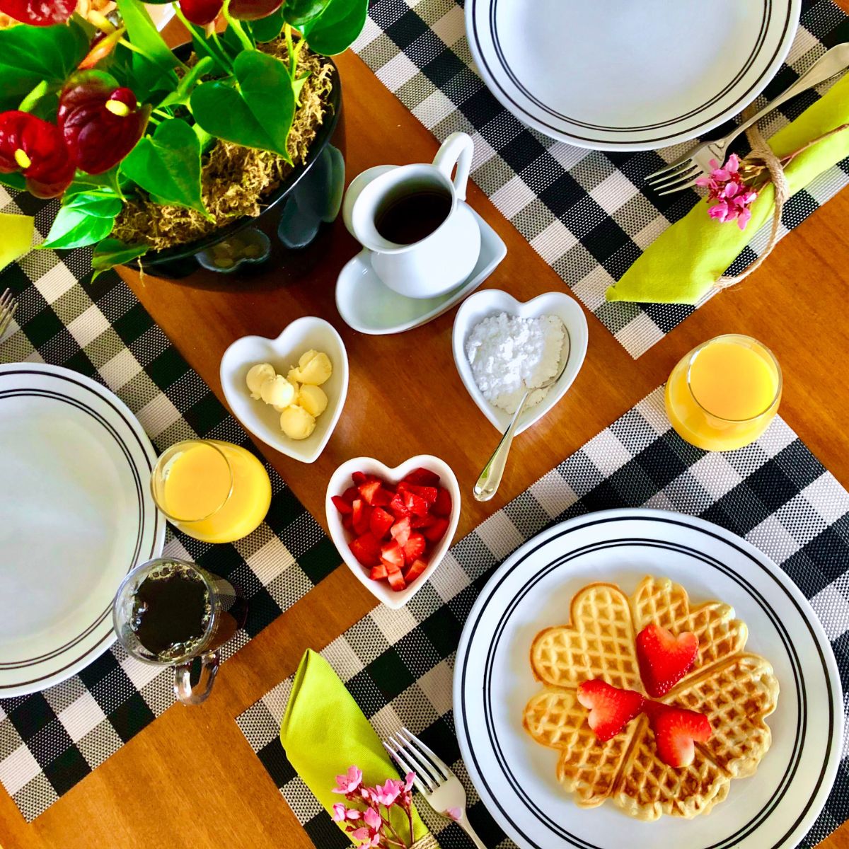 A breakfast table with homemade vegan waffles, strawberries, orange juice, and coffee.