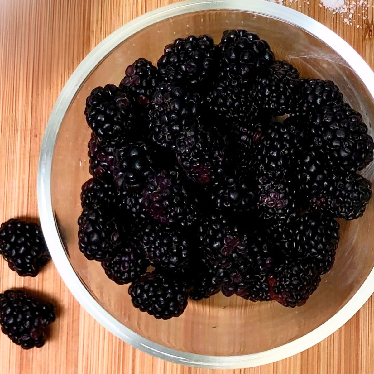A glass bowl filled with fresh blackberries.