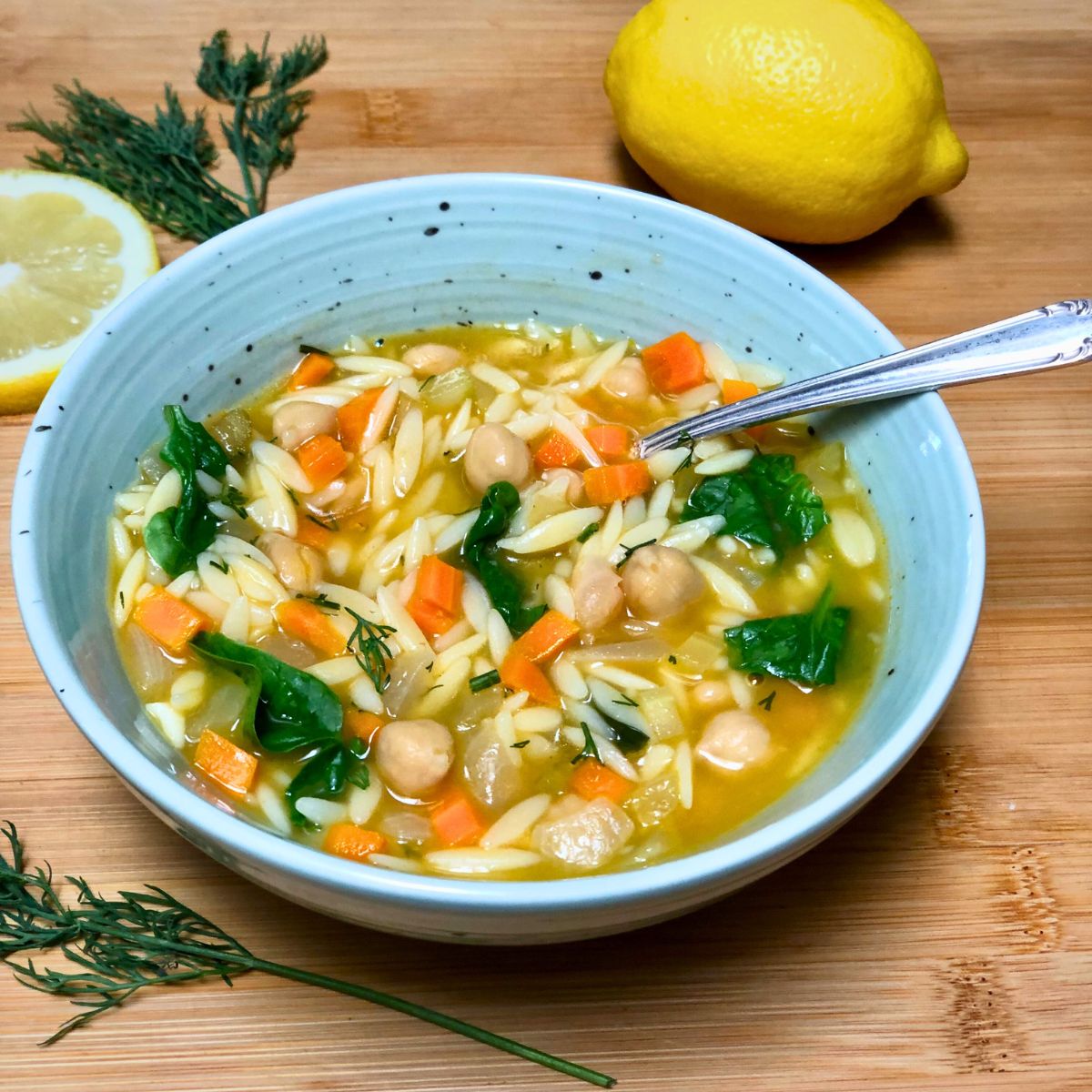A bowl of vegan Mediterranean lemon orzo soup with chickpeas and vegetables.