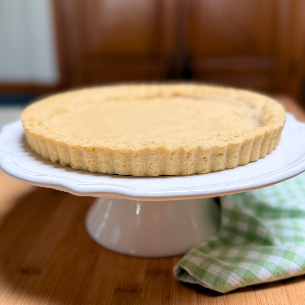 A vegan shortbread pie crust on a pedestal cake plate.