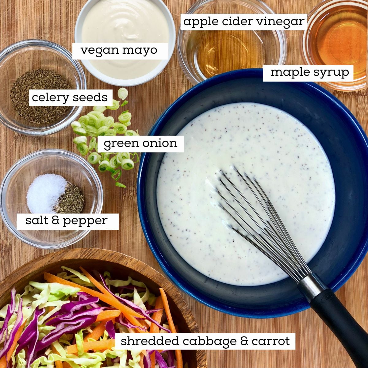 Bowls filled with ingredients for classic vegan coleslaw including shredded red and green cabbage and carrots, vegan mayo, apple cider vinegar, maple syrup, celery seeds, salt and pepper.