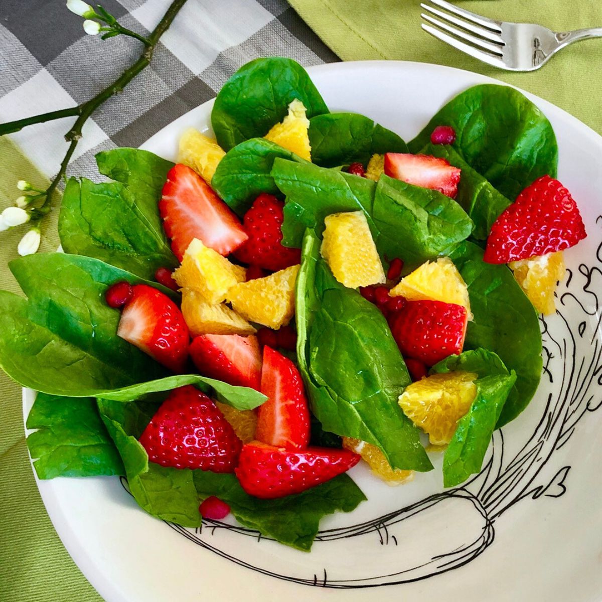 Fresh strawberries and mandarin slices in a bed of salad greens.