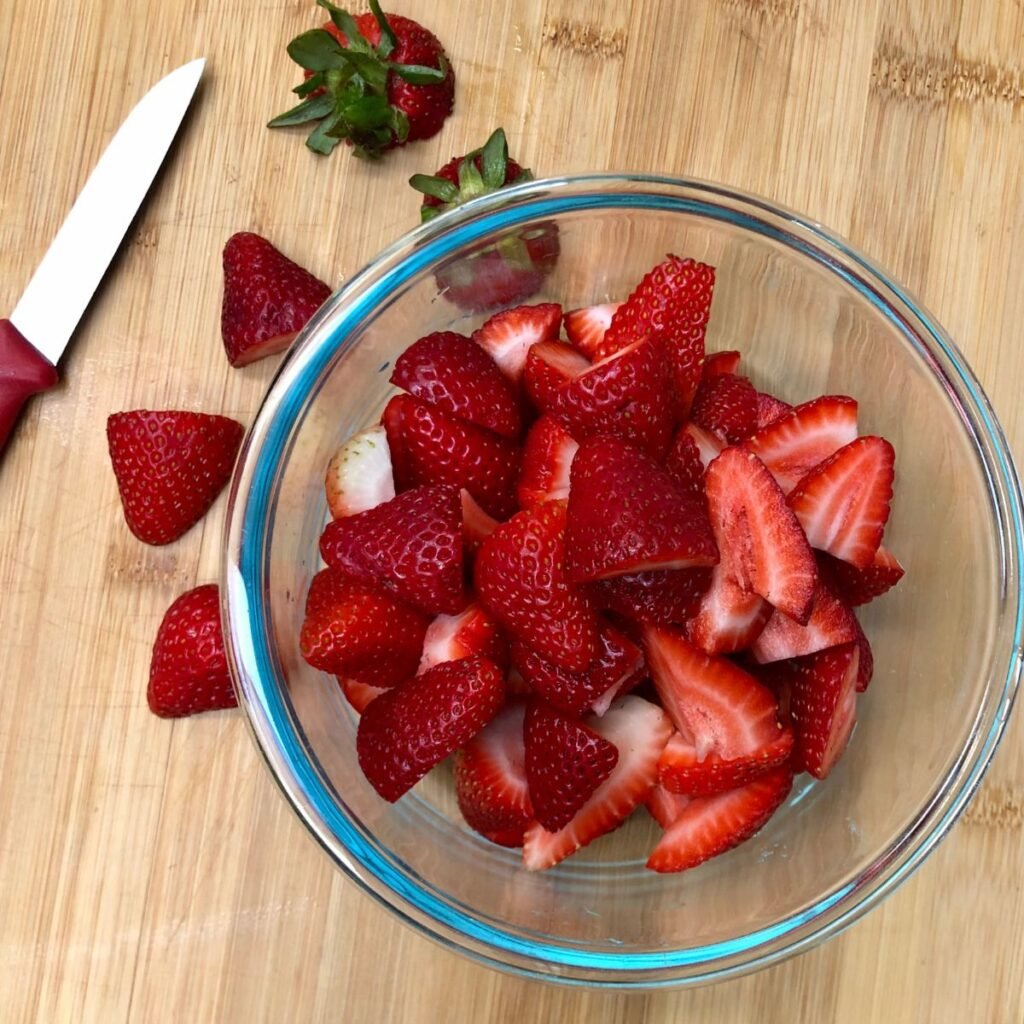 A glass bowl filled with sliced strawberries.