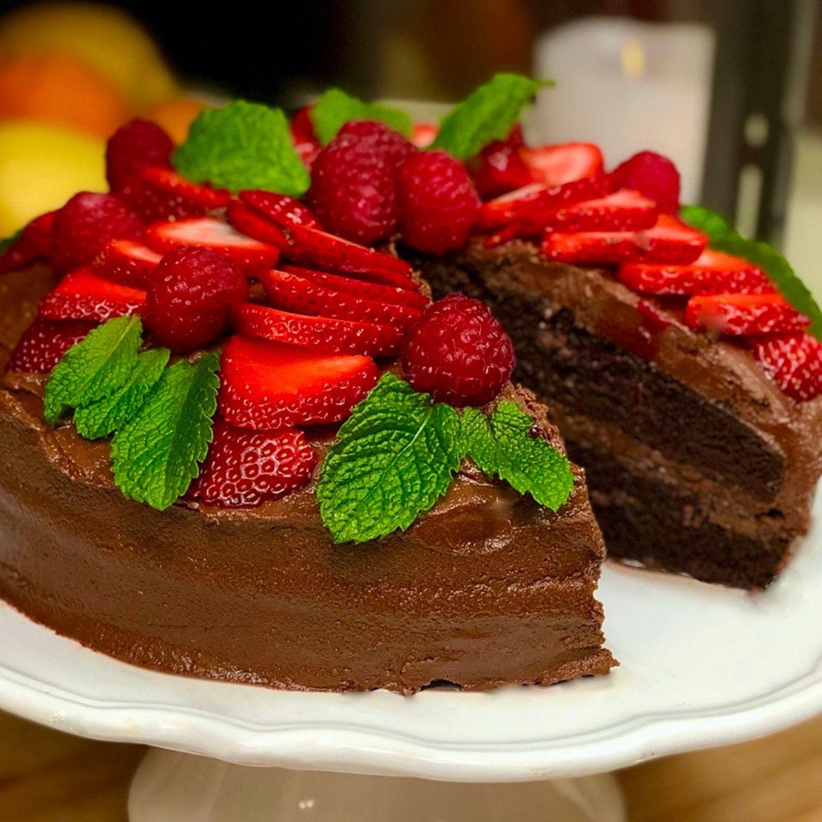 A vegan devil's food cake decorated with strawberries and raspberries.