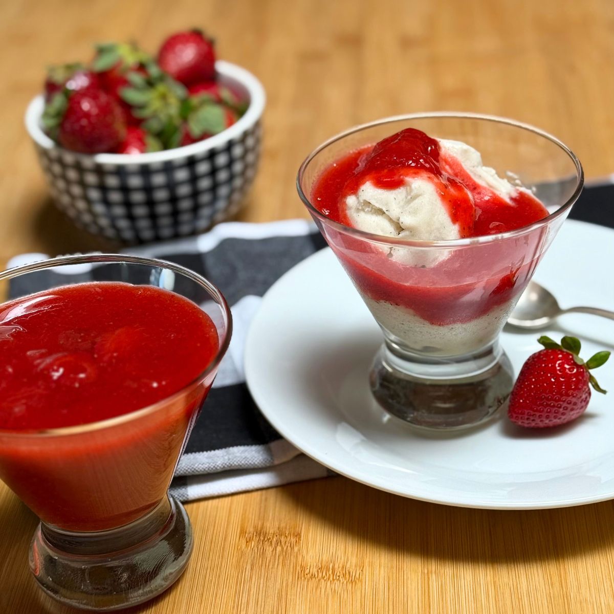 A bowl with vegan vanilla ice cream topped with homemade strawberry compote sauce.