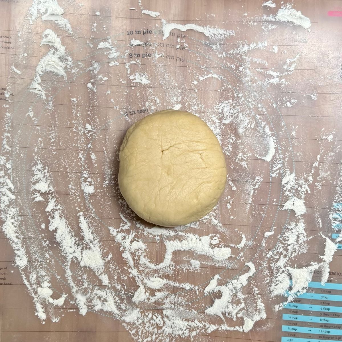A ball of vegan shortbread cookie dough on a flour dusted wood board.