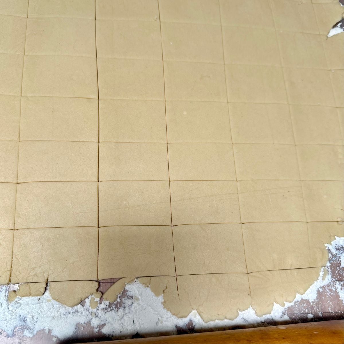 Vegan shortbread cookie dough rolled out onto a flour dusted board, cut into rectangular shapes.