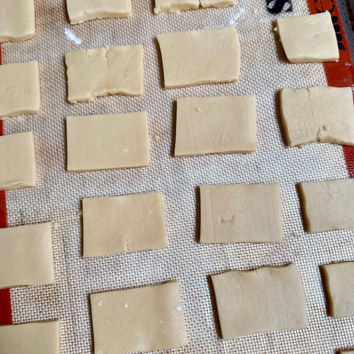 Rectangular vegan shortbread cookies on a silicone baking mat ready to be baked.
