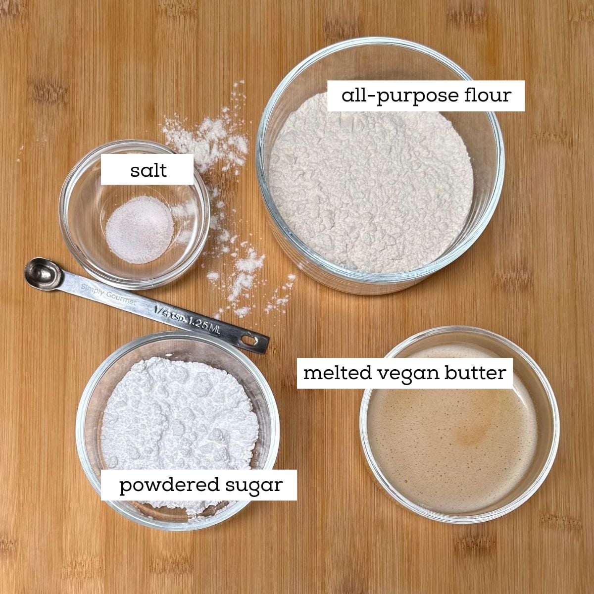 Ingredients for making a shortbread crust for classic vegan lemon bars, including all-purpose flour, powdered sugar, melted butter, and salt.