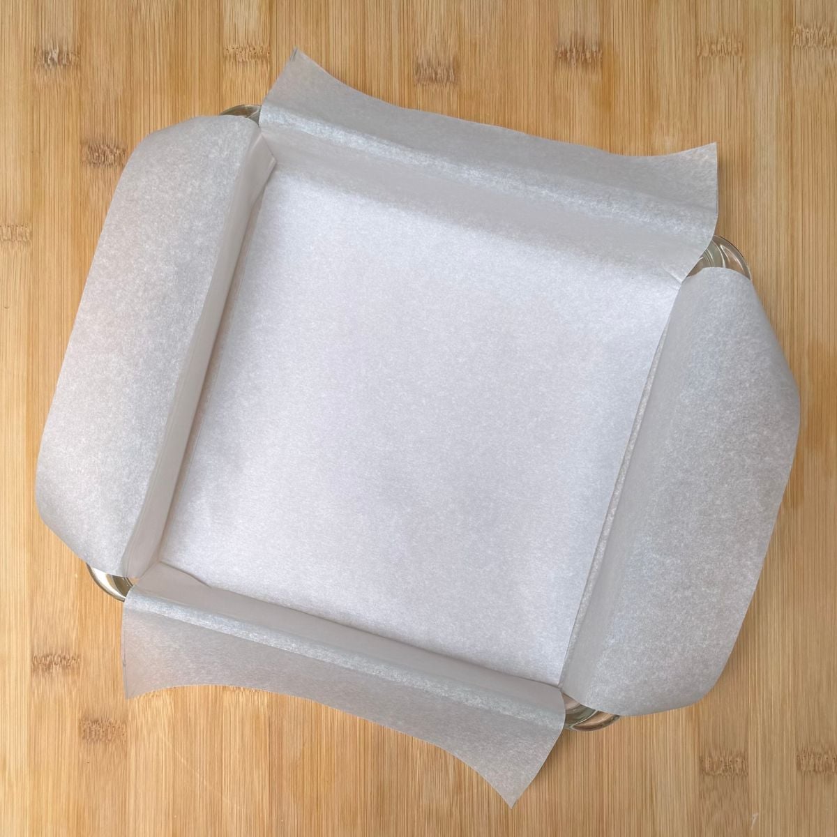 A square baking dish lined with parchment paper.