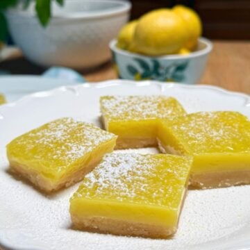 Vegan lemon bars dusted with powdered sugar on a plate.