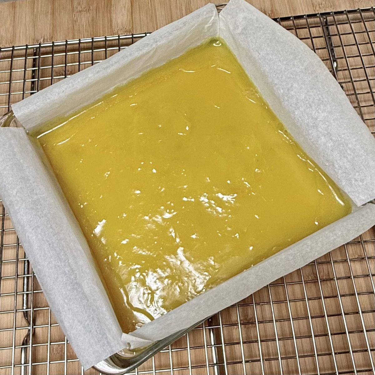 A pan of baked vegan lemon bars cooling on a wire rack.