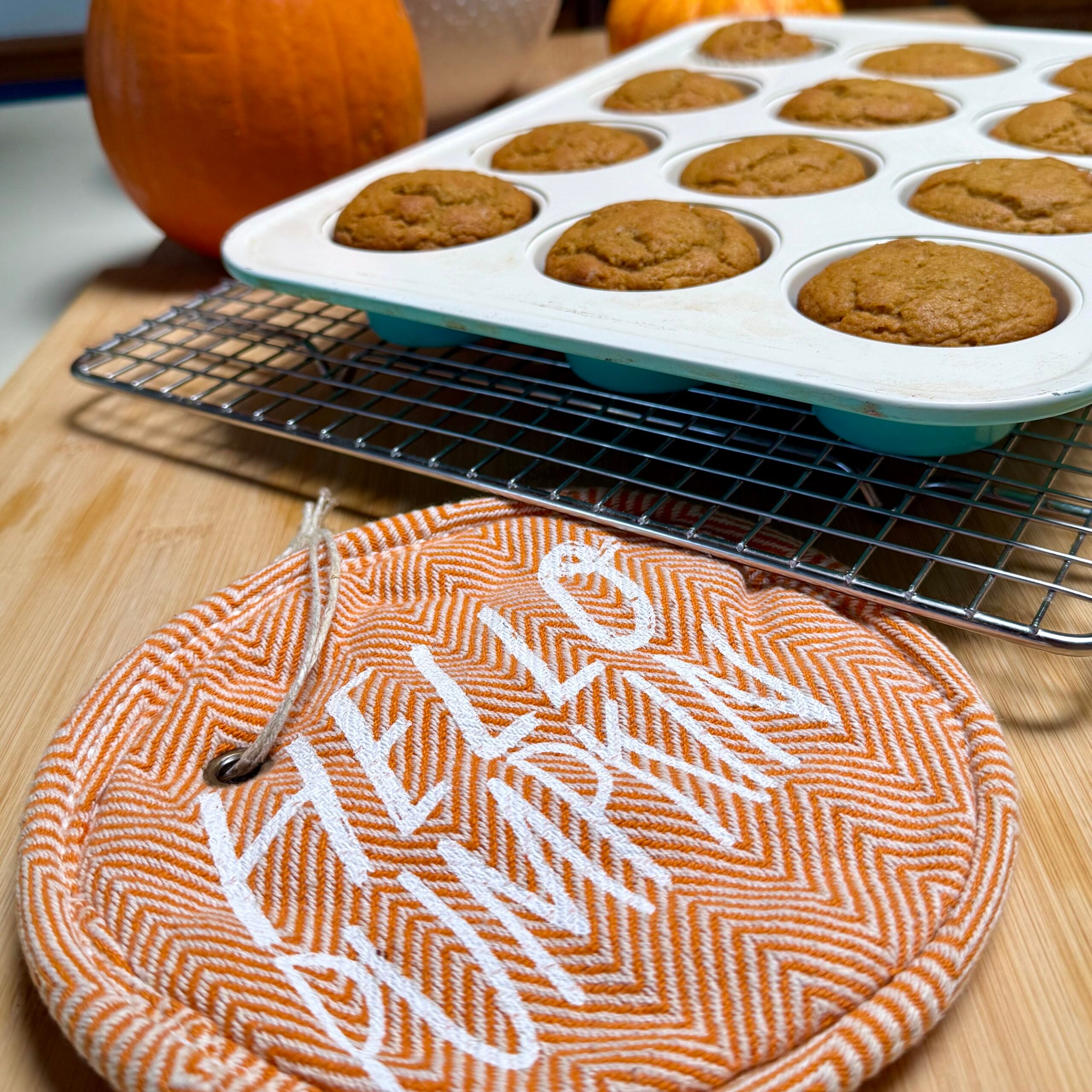 A muffin tin filled with baked vegan maple muffins, cooling on a wire rack.