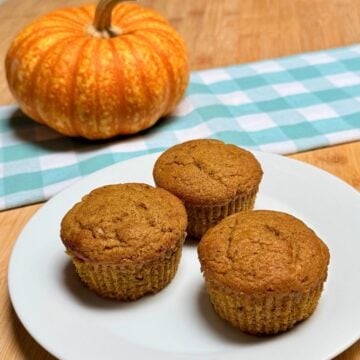 Three vegan pumpkin muffins arranged on a plate.