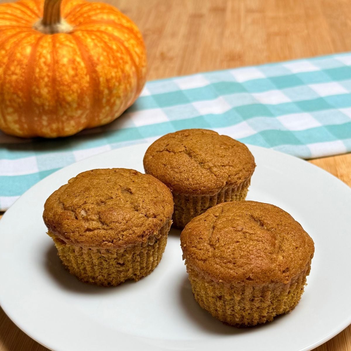Three vegan pumpkin muffins arranged on a plate.