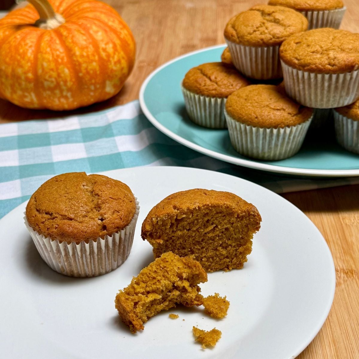 Two plates arranged with vegan pumpkin muffins, one partially eaten.