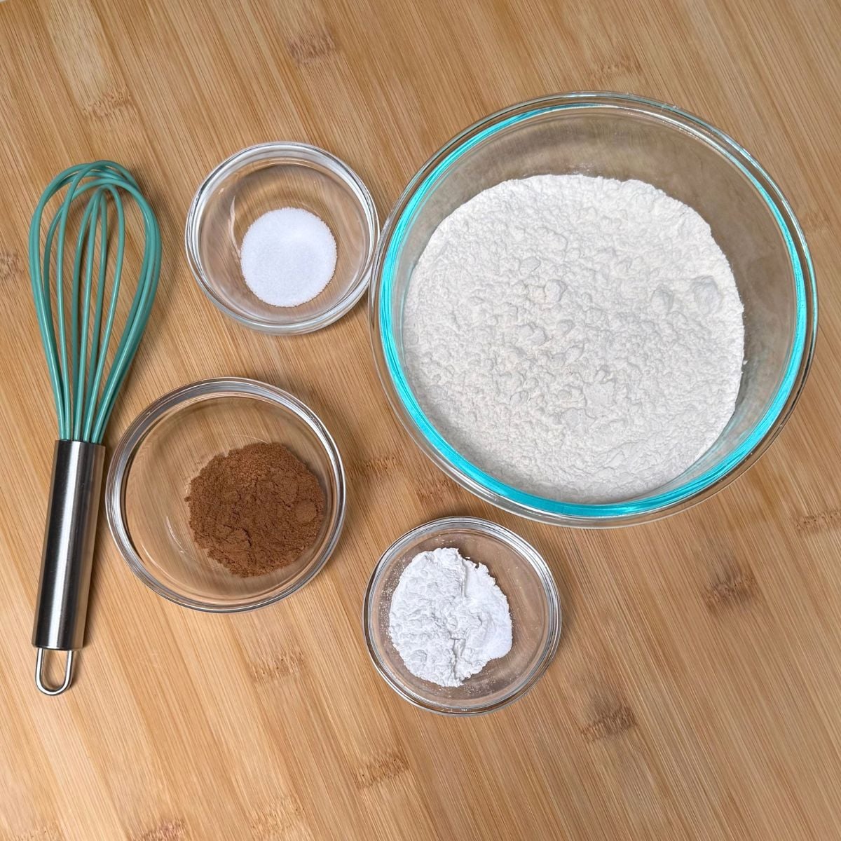 Bowls filled with dry ingredients for vegan maple pumpkin muffins including flour, baking powder, soda, salt, and pumpkin spices.