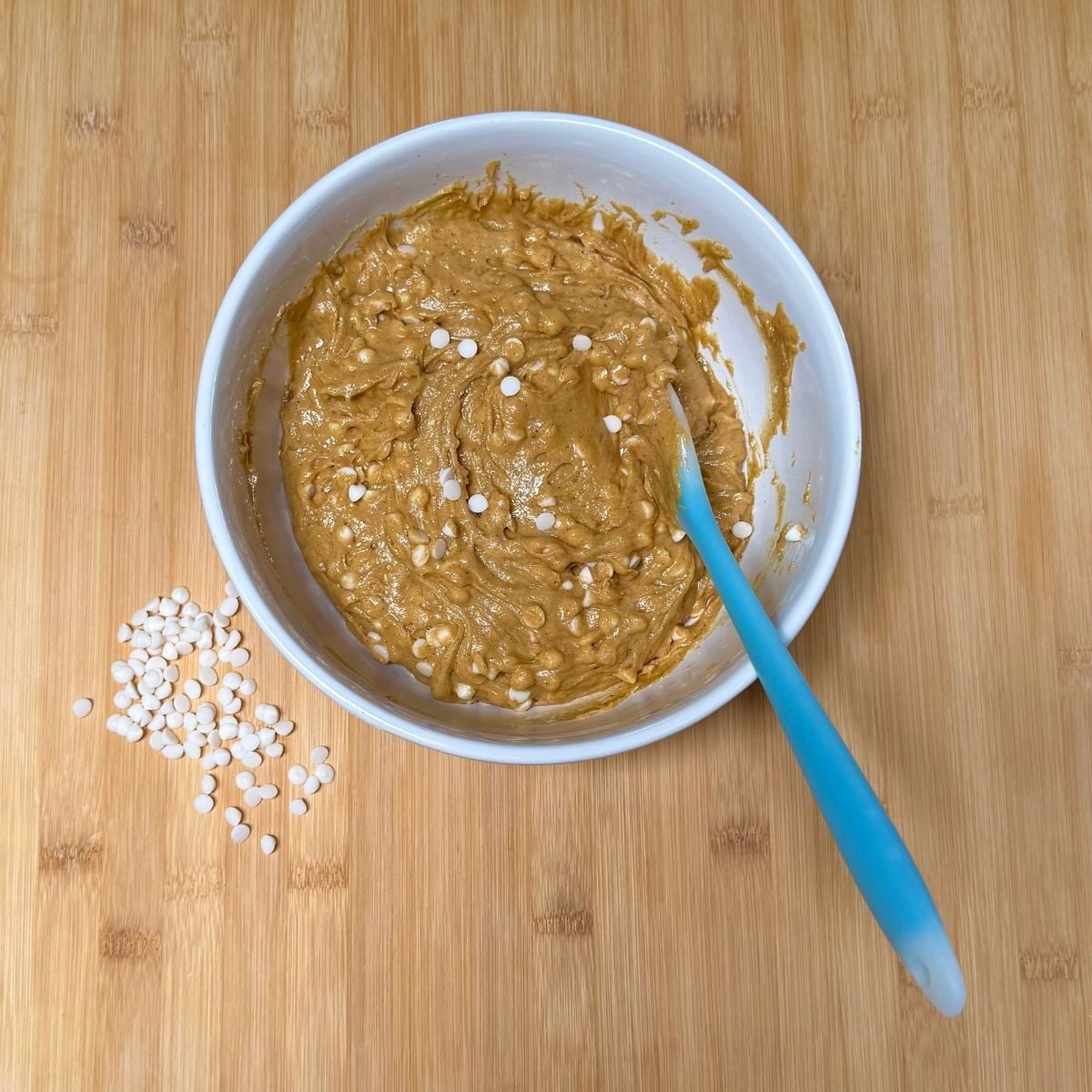 A bowl filled with vegan pumpkin cookies with white chocolate chips.