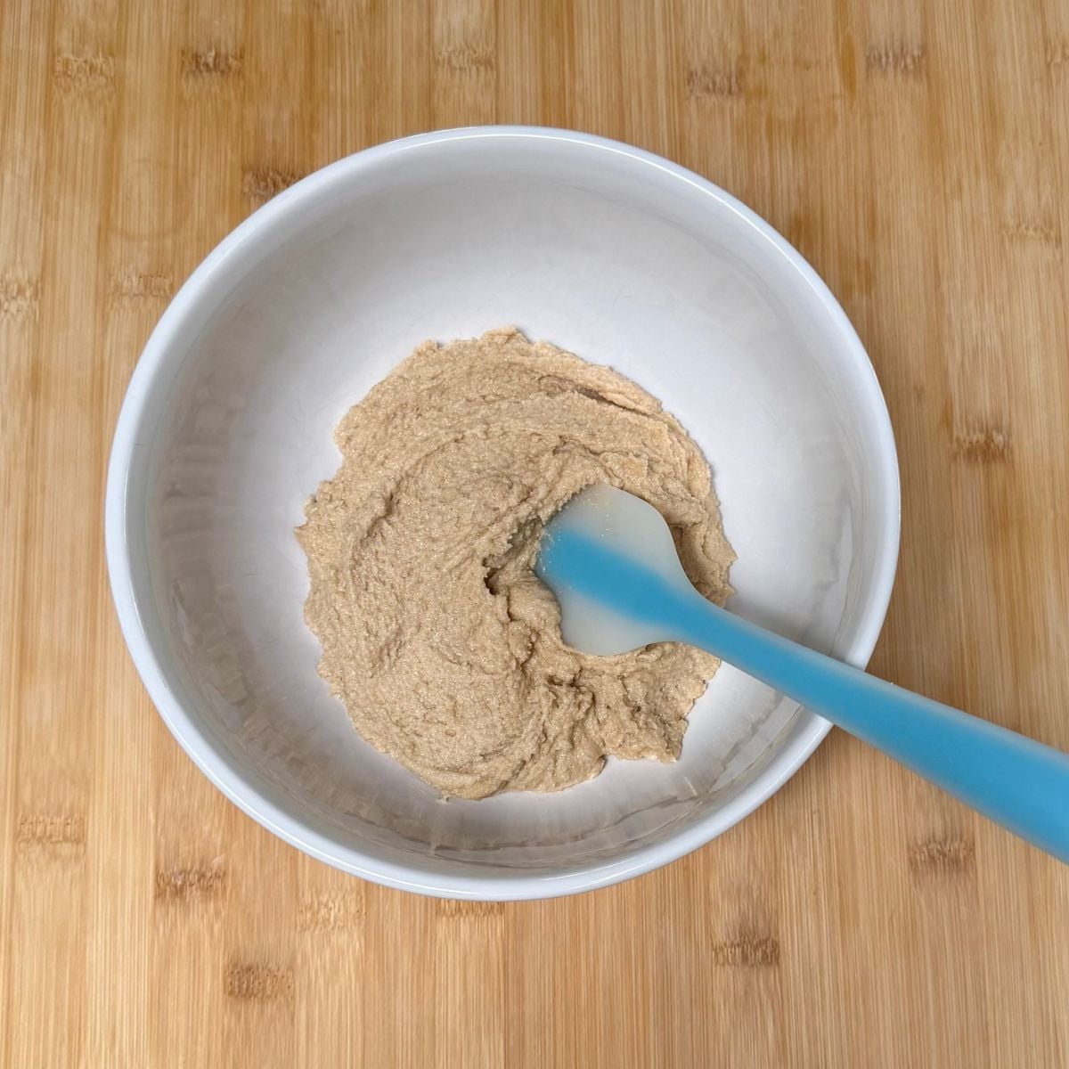 A mixing bowl with blended granulated and brown sugar, non-dairy butter, and vanilla extract.