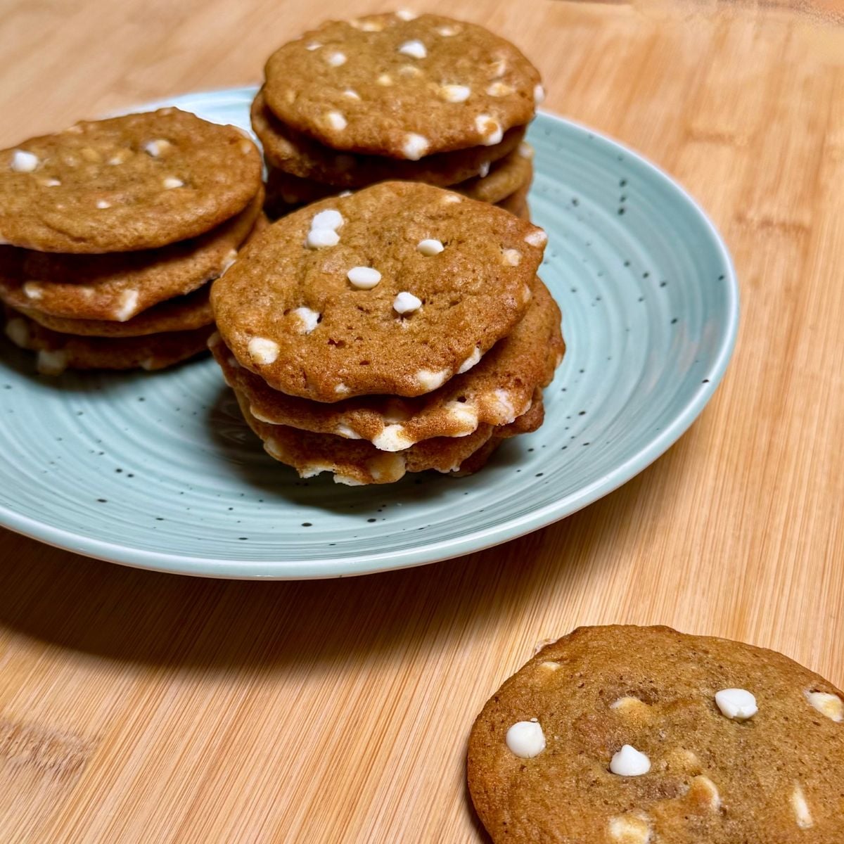 Three stacks of vegan pumpkin white chocolate chip cookies on a plate.