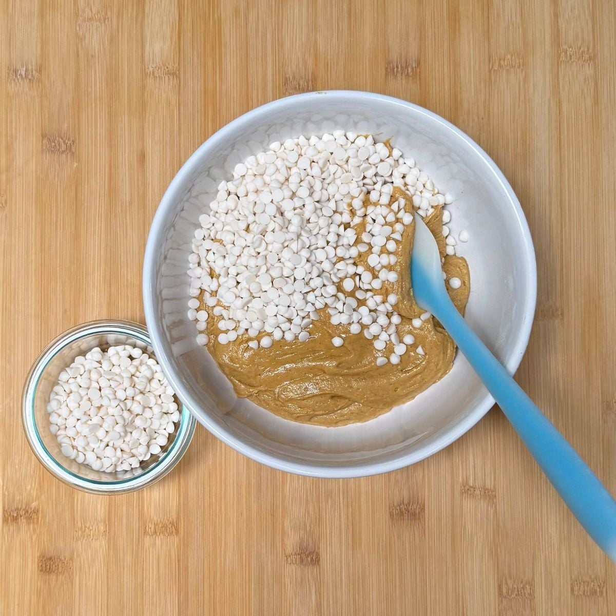 A bowl filled with vegan pumpkin cookie dough and white chocolate chips on top.